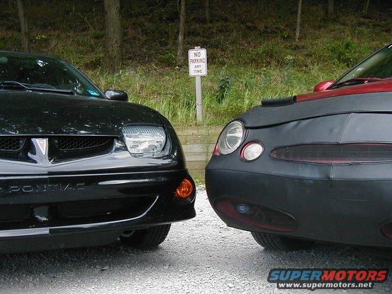 Black Pontiac and a red car with a cover parked facing each other