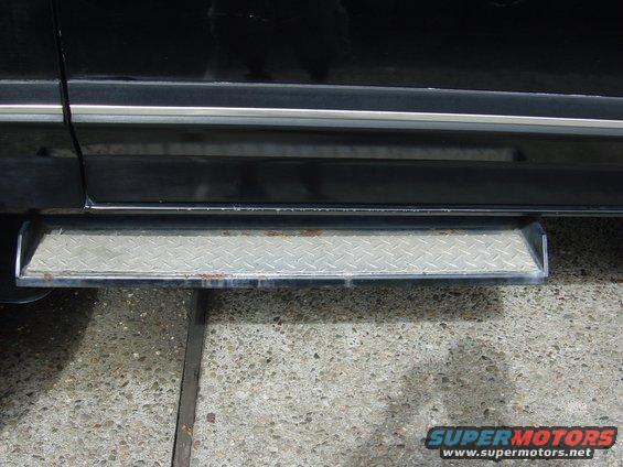 Diamond plate step bar attached to the side of a black vehicle