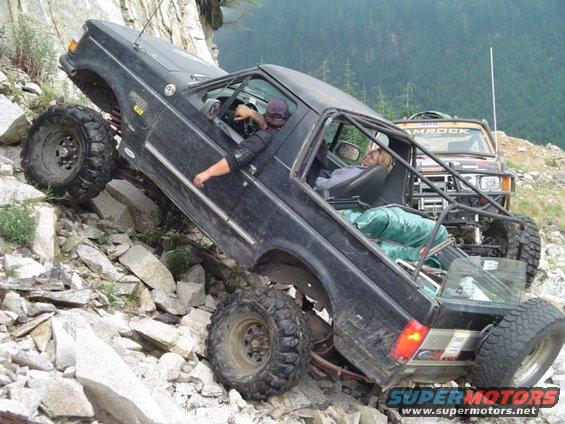 Modified 1993 Ford Bronco climbing a rocky incline with another off-road vehicle behind it