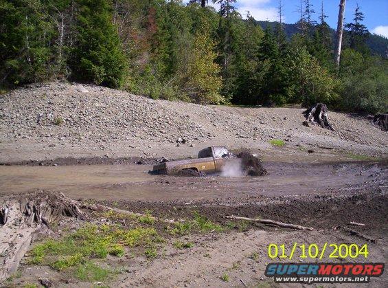 Brown pickup truck stuck in mud, splashing water