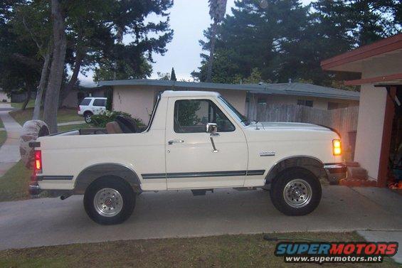 White 1990 Ford Bronco parked on a driveway, side view, with spare tire mounted on the rear