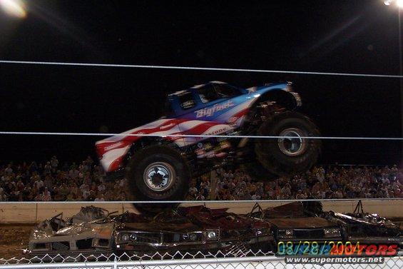 Bigfoot monster truck mid-air over crushed cars, crowd in background. Date stamp 08/28/2004