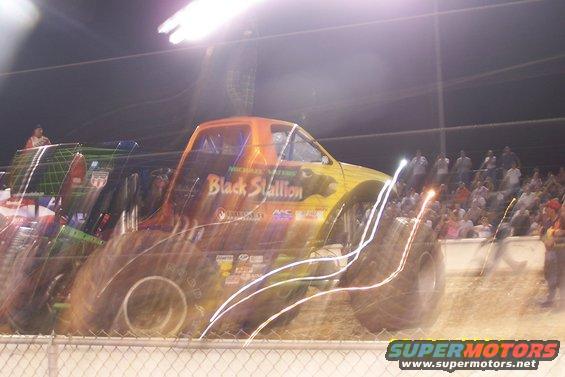 Monster truck named Black Stallion with large tires, in front of a crowd