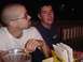 1979 Ford Bronco - Two men are seated at a table, with one holding a small sandwich and the other looking towards the camera.
