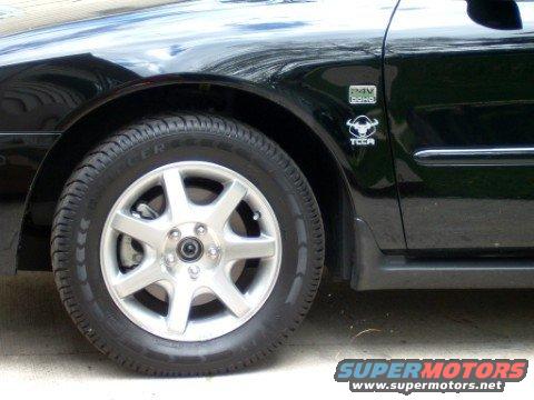 Black car fender with a silver wheel and tire. A badge reads '24V DOHC TCCA'