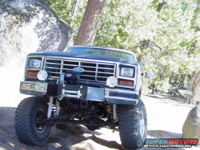 Front view of a dark blue 1986 Ford Bronco with a winch mounted on the bumper