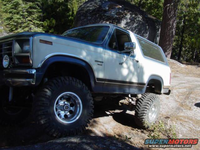 1986 Ford Bronco with lifted suspension and large tires on a rocky trail