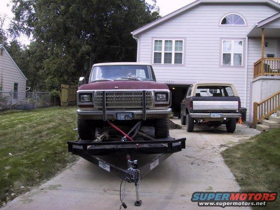 Maroon 1980s Ford Bronco on a trailer, another Bronco in background