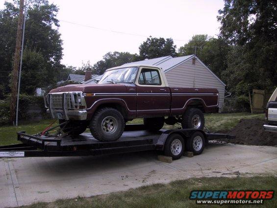 Maroon and white Ford F-Series pickup on a trailer. Has a brush guard on the front