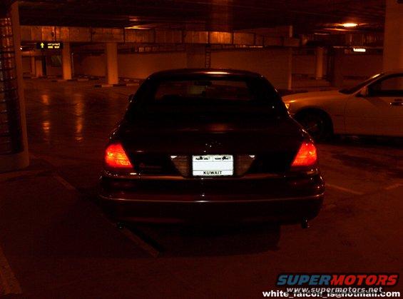Rear view of a dark sedan with a Kuwaiti license plate. Another car is visible to the right