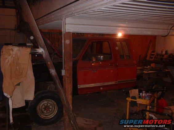 Red truck cab with chrome trim, parked indoors under a metal ceiling. A tan jacket hangs on a support beam