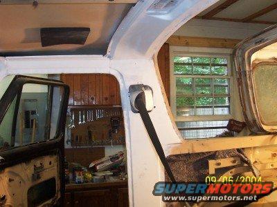 Interior view of a vehicle with door open, showing tools on wall and a window. Work is in progress