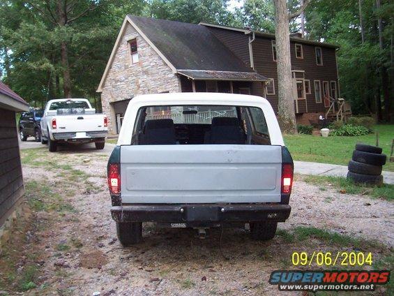 Rear view of white and green SUV with a white pickup truck behind it