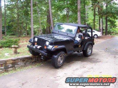 Black 1994 Jeep YJ parked on a driveway with a white car in the background