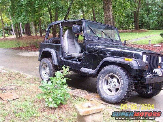 Black Jeep Wrangler parked outside with trees in the background