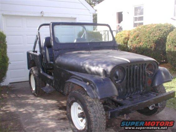 Black Jeep CJ-5 with white rims and roll bar, parked in driveway