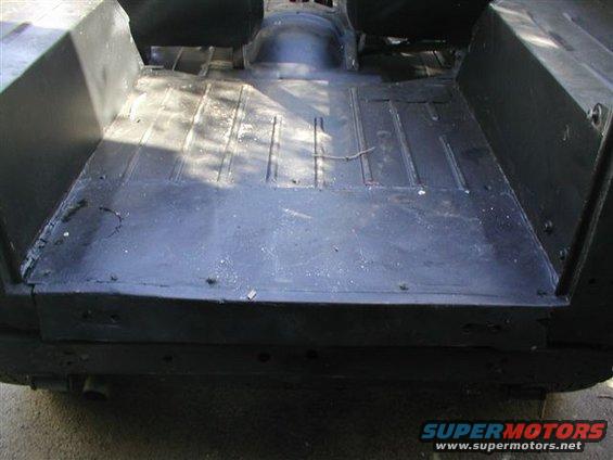 Rear interior floor of a vehicle, showing ribbed metal and black paint