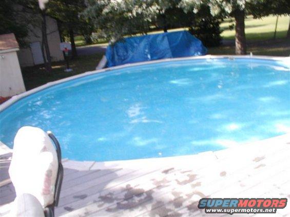 above-ground pool on wooden deck, blue tarp covers something in background