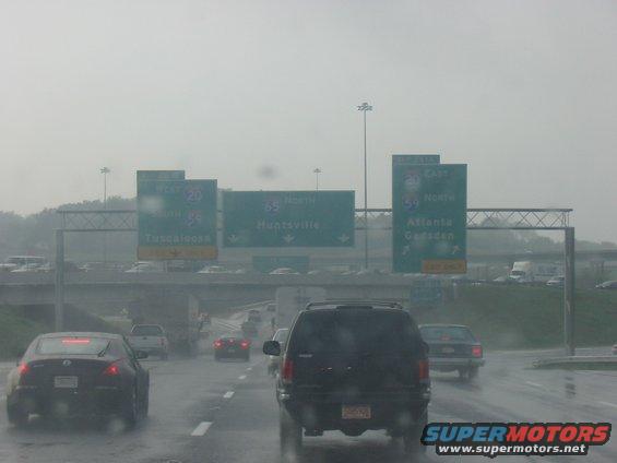 Black SUV from behind on a wet highway with overhead signs