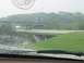 1988 Ford Bronco - Raindrops on the windshield obscure the view of highway overpasses and green hills.