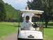 1988 Ford Bronco - Two individuals ride in a golf cart on a sunny day at the golf course.