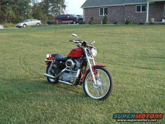 Red motorcycle with chrome accents parked on a grassy lawn in front of a house