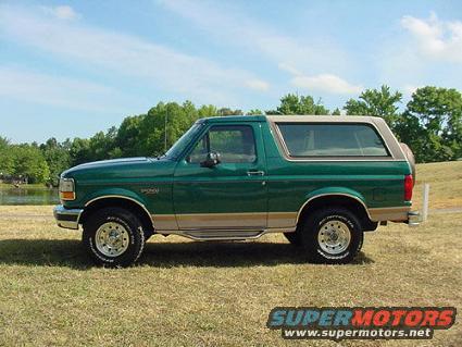 Green 1996 Ford Bronco with tan trim and removable top, parked on grass