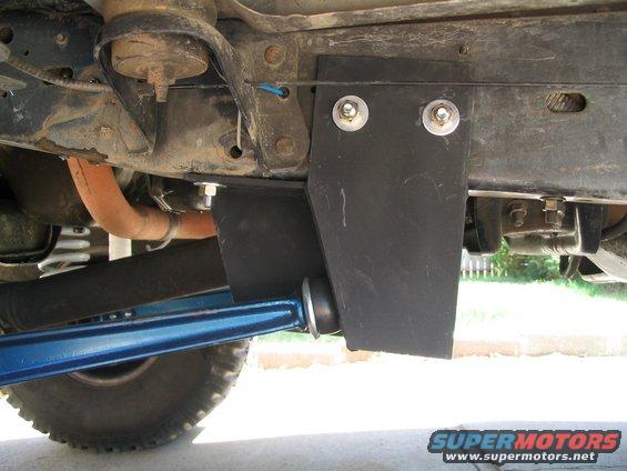 Aftermarket blue control arm and black bracket bolted to vehicle frame