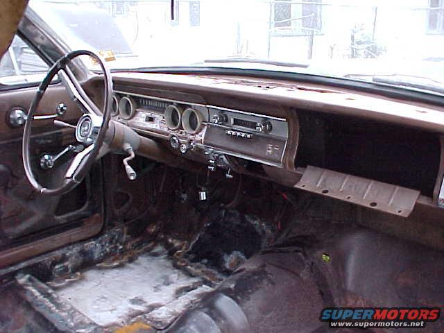 car interior with steering wheel, dashboard, and rusted floor
