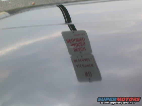 Reflection of a tag on a car's hood, showing text about service and a bench