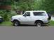 1992 Ford Bronco - A white 1992 Ford Bronco is parked on the side of a road with a house in the background.