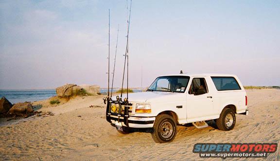 White 1996 Ford Bronco with fishing rod holder on beach