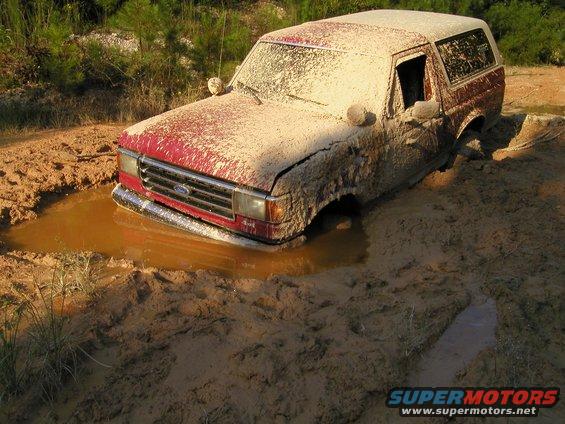 Red SUV stuck in mud, front grille visible
