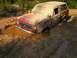 1989 Ford Bronco - This red SUV is deeply stuck in a muddy ditch, with its front end submerged in brown water.