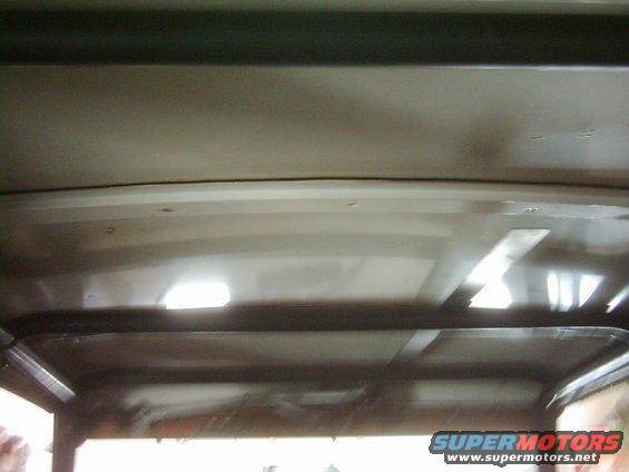 Interior roof structure of a vehicle with visible support beams and lighting