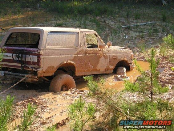 Muddy SUV stuck in a muddy ditch, front wheel submerged