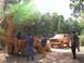 1989 Ford Bronco - A group of people stand around a mud-caked SUV and a yellow backhoe in a wooded area.