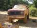 1989 Ford Bronco - This mud-caked 1987 Ford Bronco is seen from the front, its red paint barely visible beneath layers of dirt.