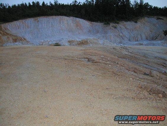 Quarry scene with layered rock formations and sandy ground