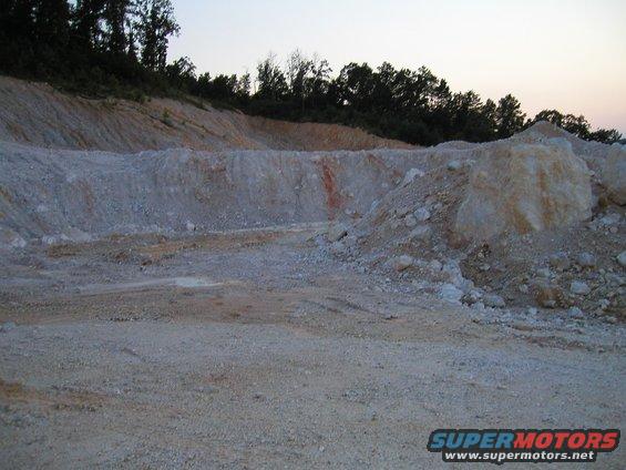 Quarry with dirt piles and trees under a dusky sky