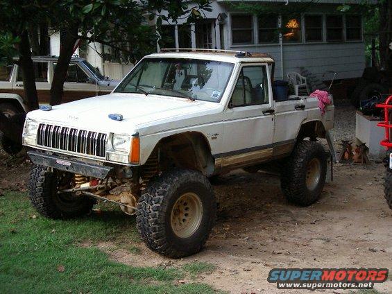 White Jeep Comanche pickup, 3q-front view, lifted with off-road tires