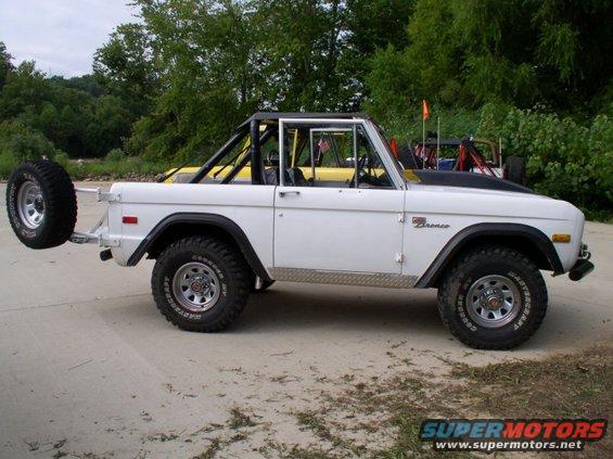 White 1967 Ford Bronco with roll cage and spare tire on rear