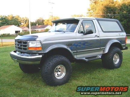 Silver 1992 Ford Bronco with blue flames, lifted suspension, and aftermarket wheels