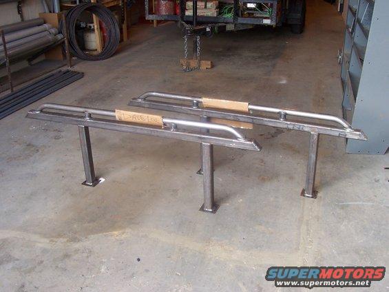 Two metal sliders with cardboard on them, standing on legs in a garage
