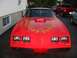 1985 Ford Bronco - A red 1981 Pontiac Firebird Trans Am is parked in front of a building, with other vehicles visible in the background.