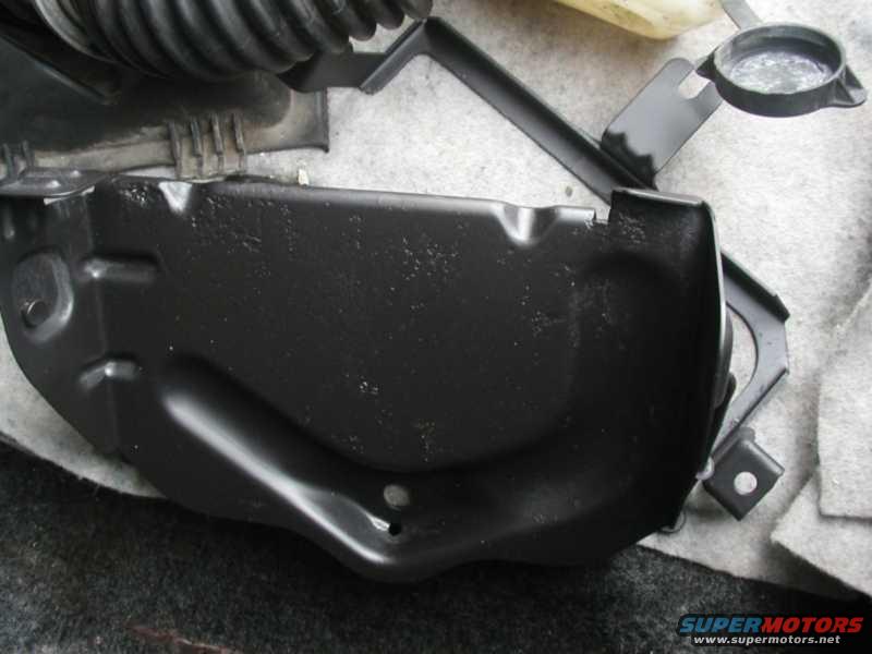 Black painted metal engine bay component with mounting bracket attached