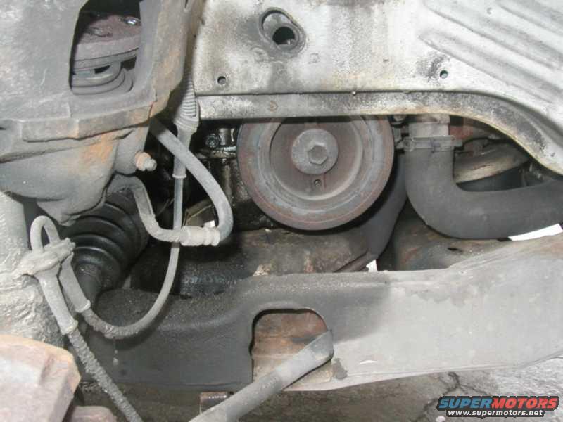 Close-up of engine parts including a pulley, hoses, and suspension components