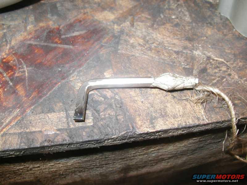 Allen wrench with twine tied around one end, resting on a wooden surface