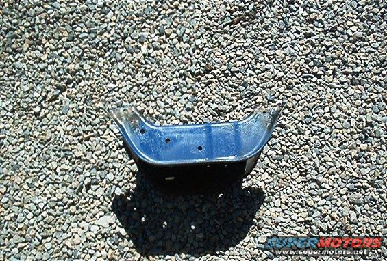 Blue metal automotive part on gravel with website watermark