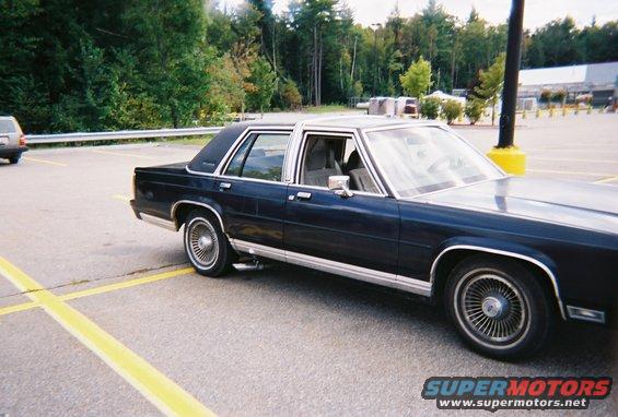 1990 Ford Crown Victoria LTD parked, showing its side and front quarter. Another vehicle is visible in the background